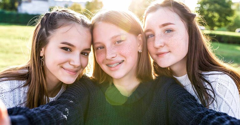 Großaufnahme von drei Teenagerinnen im Garten, während die Sonne im Hintergrund untergeht.